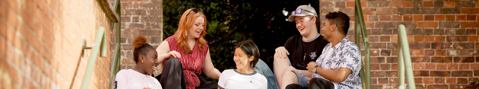 Find your place at Keele. Students sat on campus socialising. 